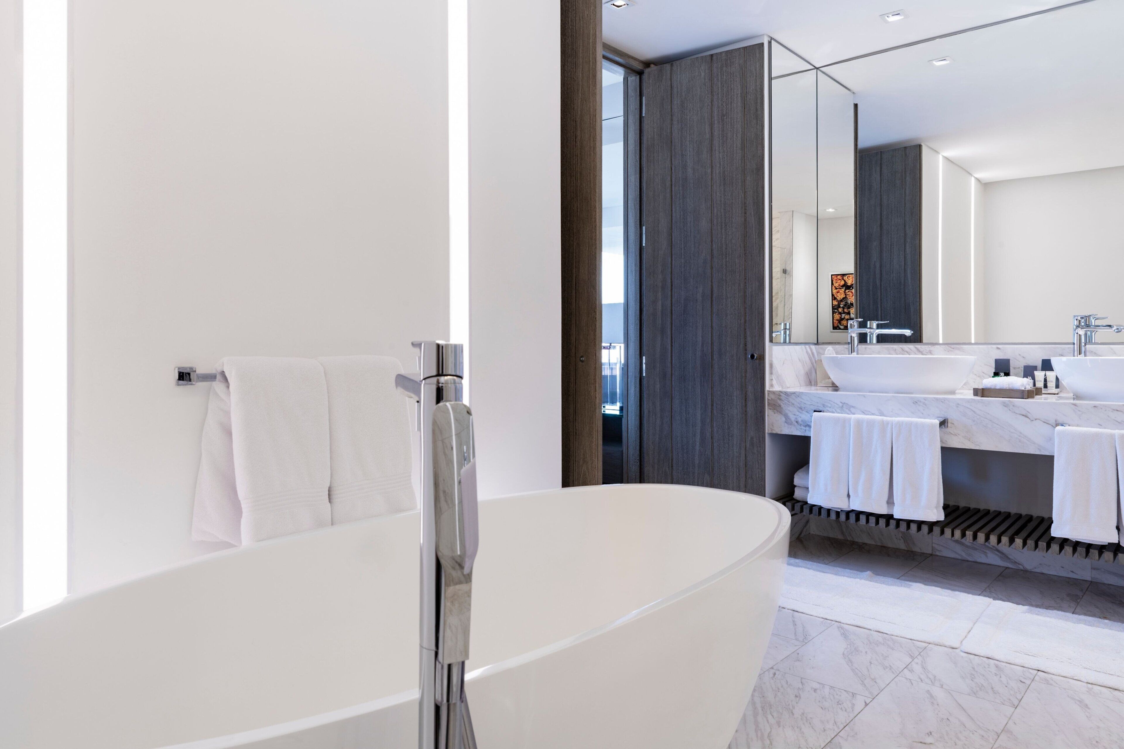 Ein modernes Badezimmer mit freistehender Badewanne, einem großen Spiegel und einem Waschtisch mit zwei Waschbecken.