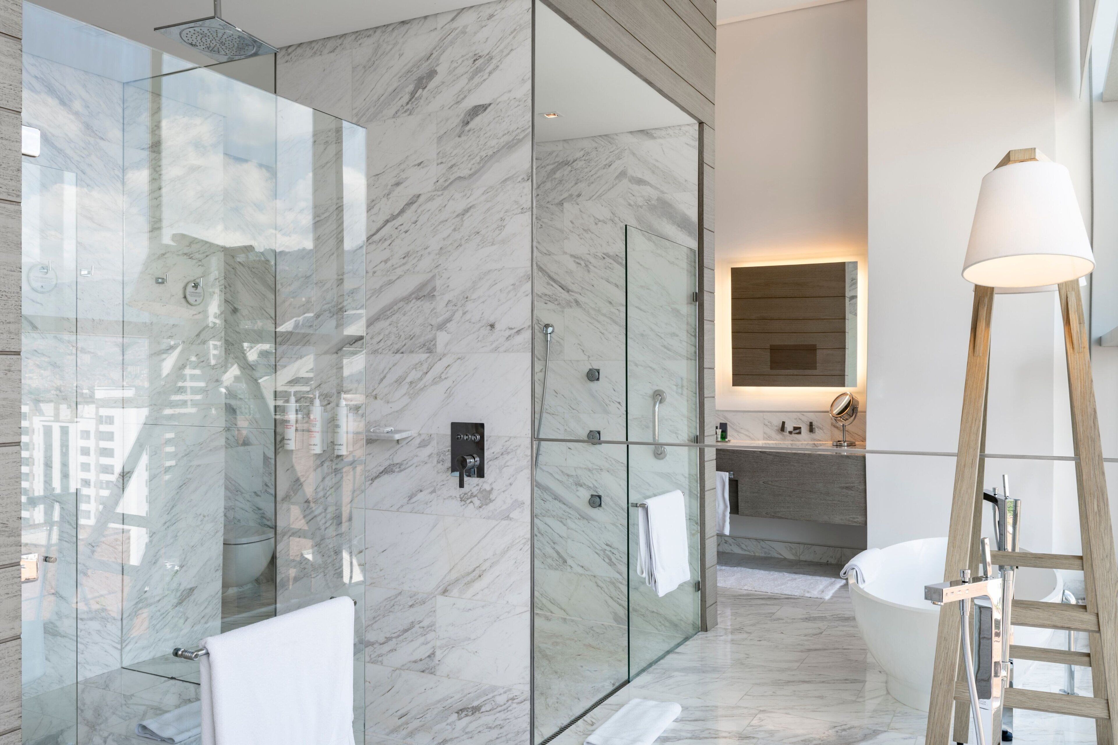 A modern bathroom with a glass-enclosed shower, a freestanding bathtub, and a wooden ladder.