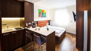Cozy retreat with a kitchenette, single bed, and a window with sheer curtains.