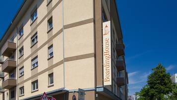 A multi-story hotel with a beige facade, balconies, and a sign indicating a 30 km/h speed limit.