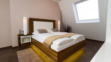 A modern bedroom with a wooden bed, white linens, a bedside table with a lamp, and a window with blinds.