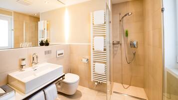 A modern bathroom with a large sink, toilet, and walk-in shower.