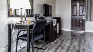 A hotel room with a desk, chair, television, and a door with a sign. - Lakeview Lodge Motel (Lakeview)