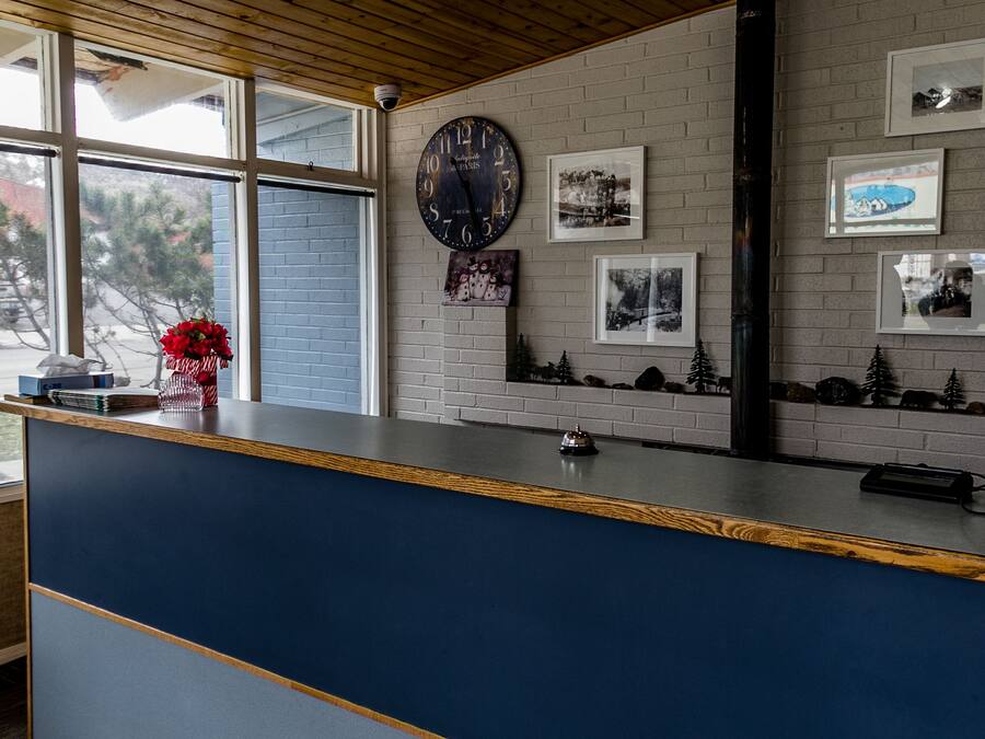 A reception desk with a clock, framed pictures, and a vase with red flowers.