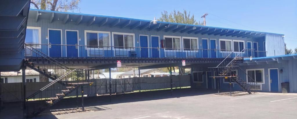 Un bâtiment à deux étages, à la façade bleue, doté d’une galerie couverte et d’un parking.