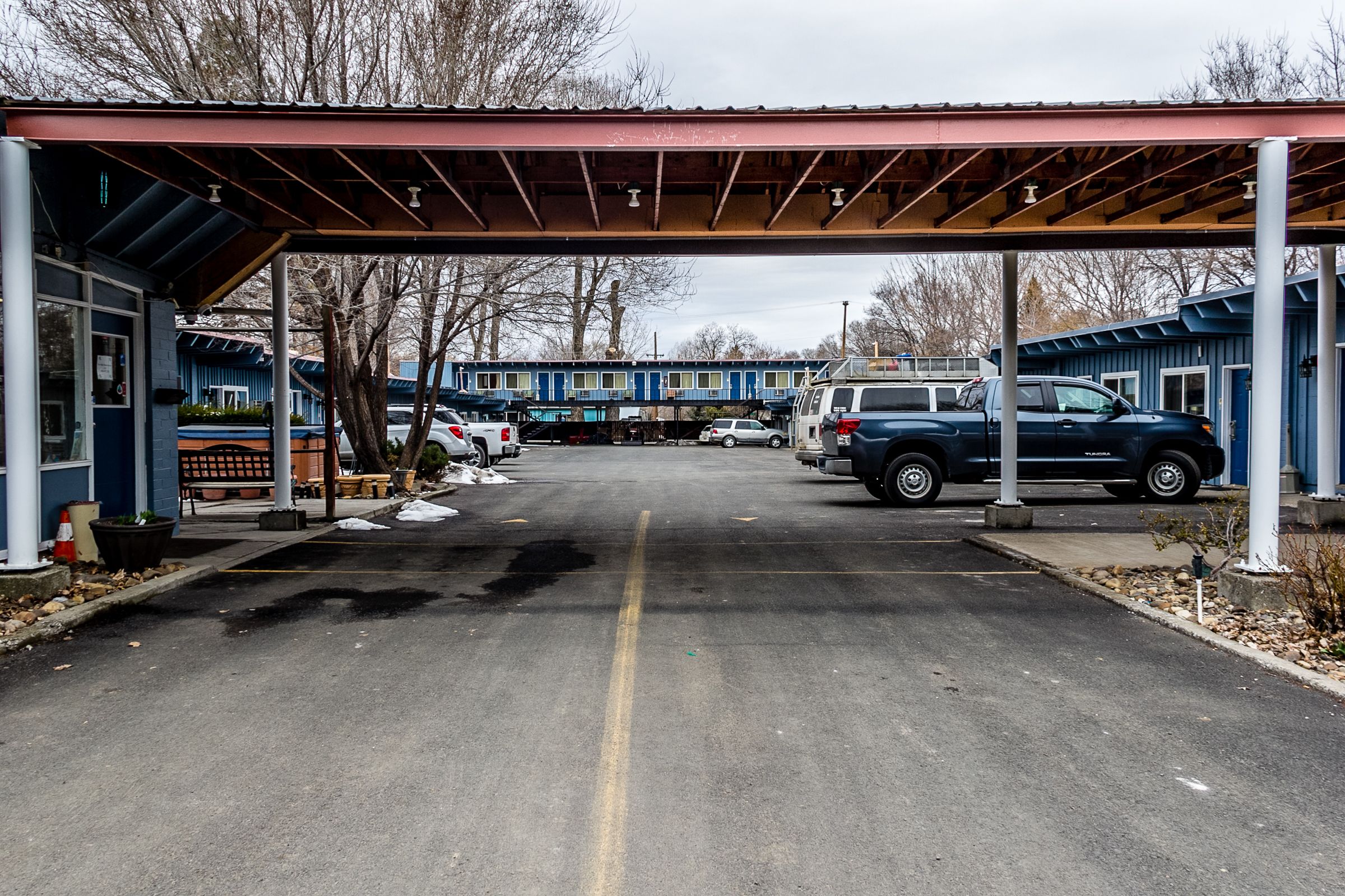 Un parking doté d’une allée couverte qui mène à une rangée de bâtiments bleus.
