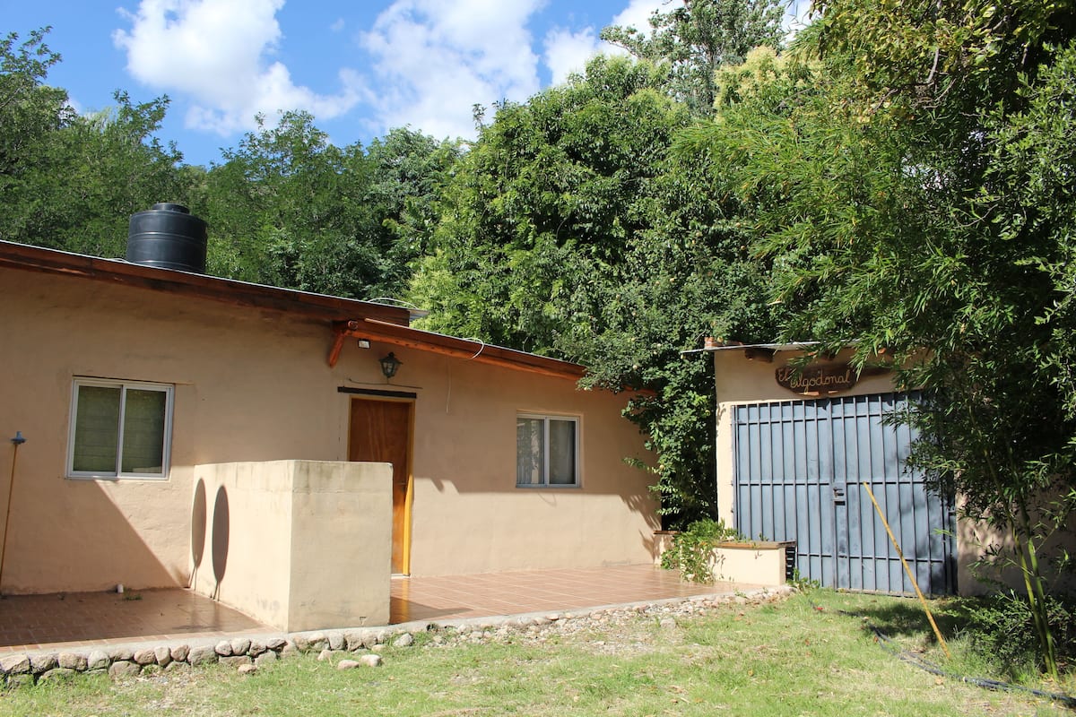 A house with a large water tank on the roof, a garage, and a small garden area.