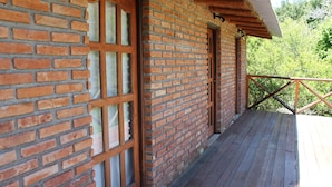 A brick building with a wooden deck and a metal railing. - Cabañas El Algodonal (Nono)