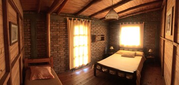 A cozy room with a wooden bed, a bench, and a brick wall.