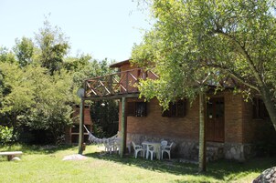 A brick building with a wooden pergola, outdoor seating, and a hammock.