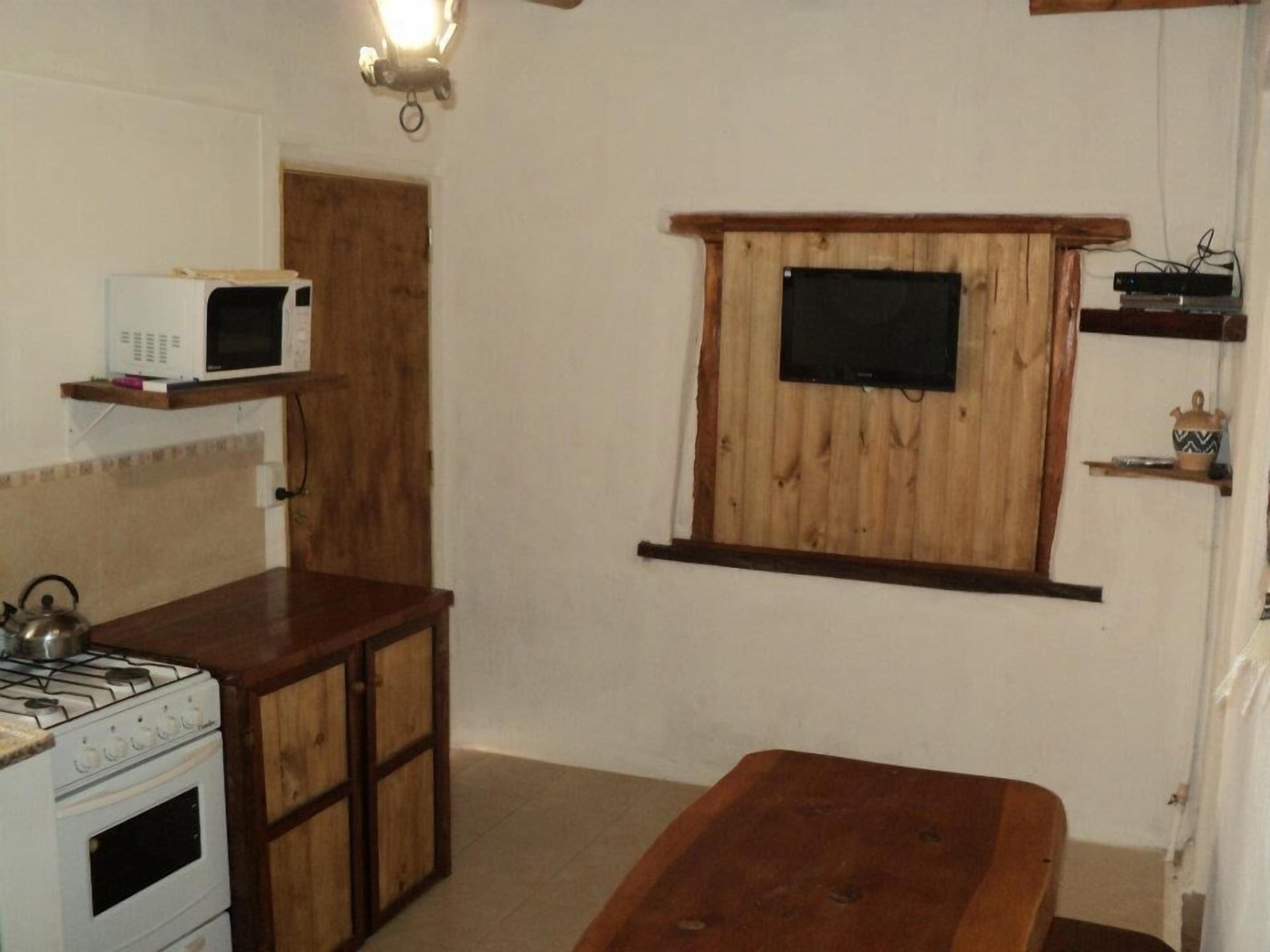 A compact kitchen with a gas stove, a microwave, and a wooden cabinet.