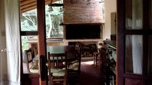 A rustic kitchen with a brick fireplace, wooden furniture, and a view of the outdoors. - Cabañas El Algodonal (Nono)