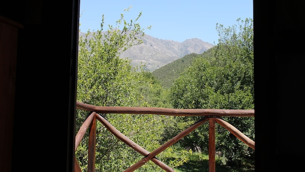 A view through a wooden railing of a mountainous landscape with dense greenery and a clear sky. - Cabañas El Algodonal (Nono)