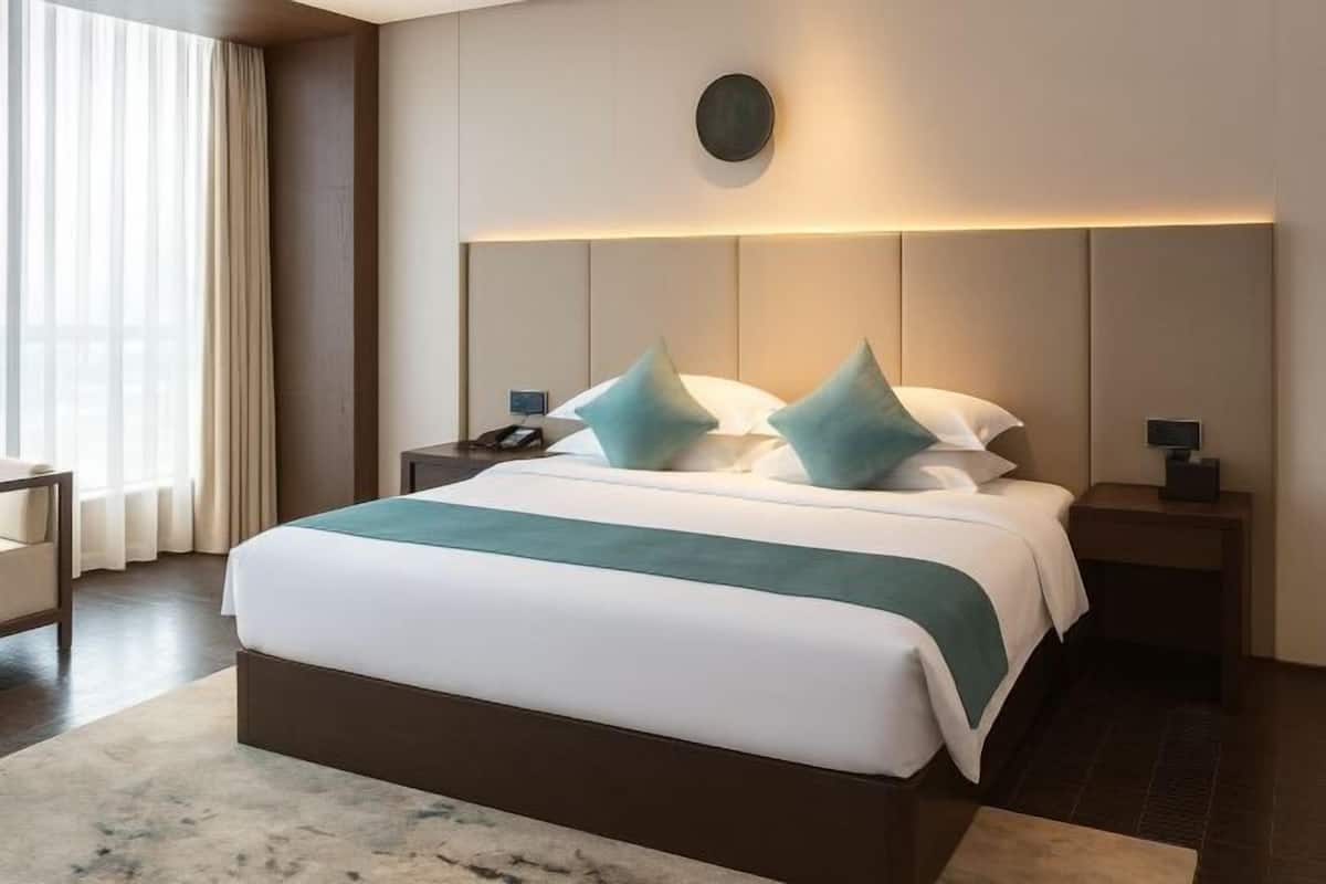 Una habitación de hotel moderna con una cama grande, dos mesitas de noche, un escritorio y una ventana con cortinas.