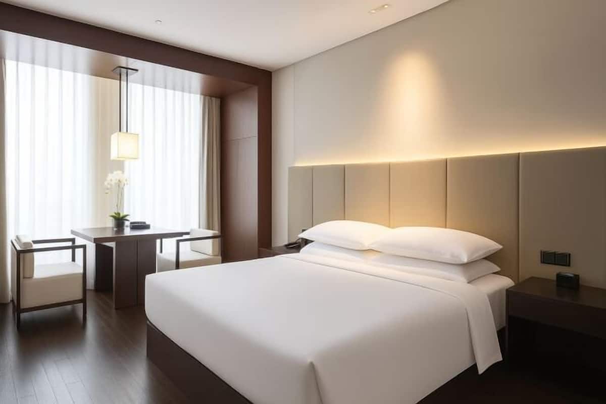 Una habitación de hotel con cama, mesita de noche, lámpara y un escritorio con silla.