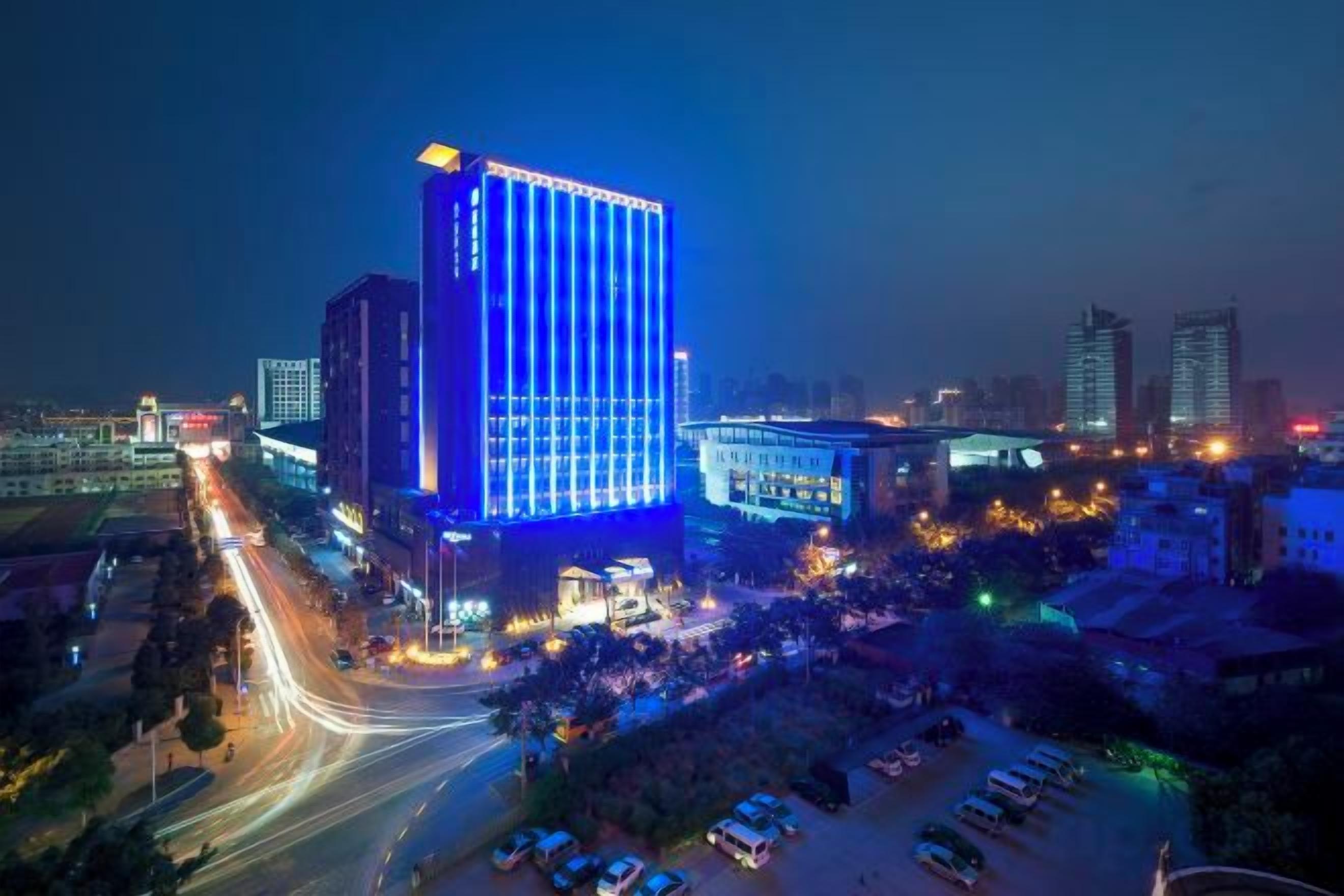 A cityscape at night with a prominent building lit in blue.