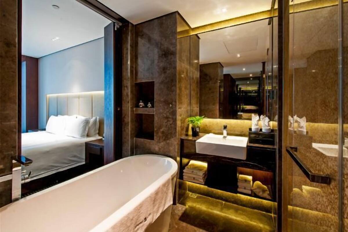 Un baño moderno con una bañera independiente, un tocador con espejo y una cama con cabecera.