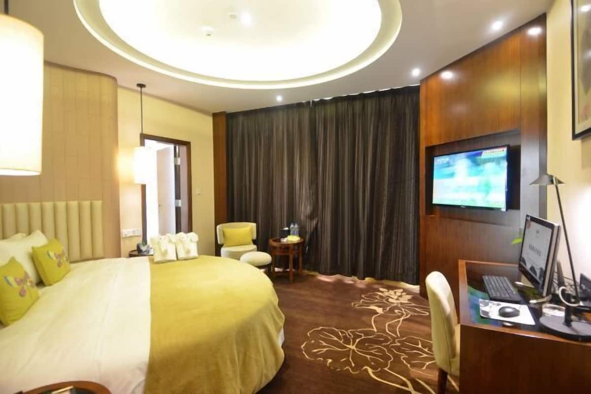 A hotel room with a bed, a desk with a computer, a television, and a chair.
