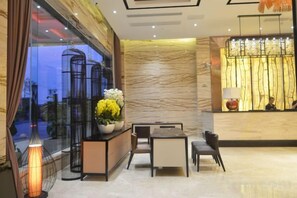A hotel lobby with a reception desk, seating area, and a large window with curtains. - Xiangtan Mingyi Hotel (Bantang City Railway Station Store) (Xiangtan)