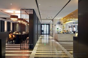 A hotel lobby with a check-in counter, seating area, and a decorative partition. - Xiangtan Mingyi Hotel (Bantang City Railway Station Store) (Xiangtan)