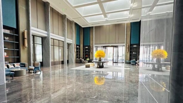 Eine großzügige Lobby mit poliertem Marmorboden, Sitzbereichen und großen Fenstern.