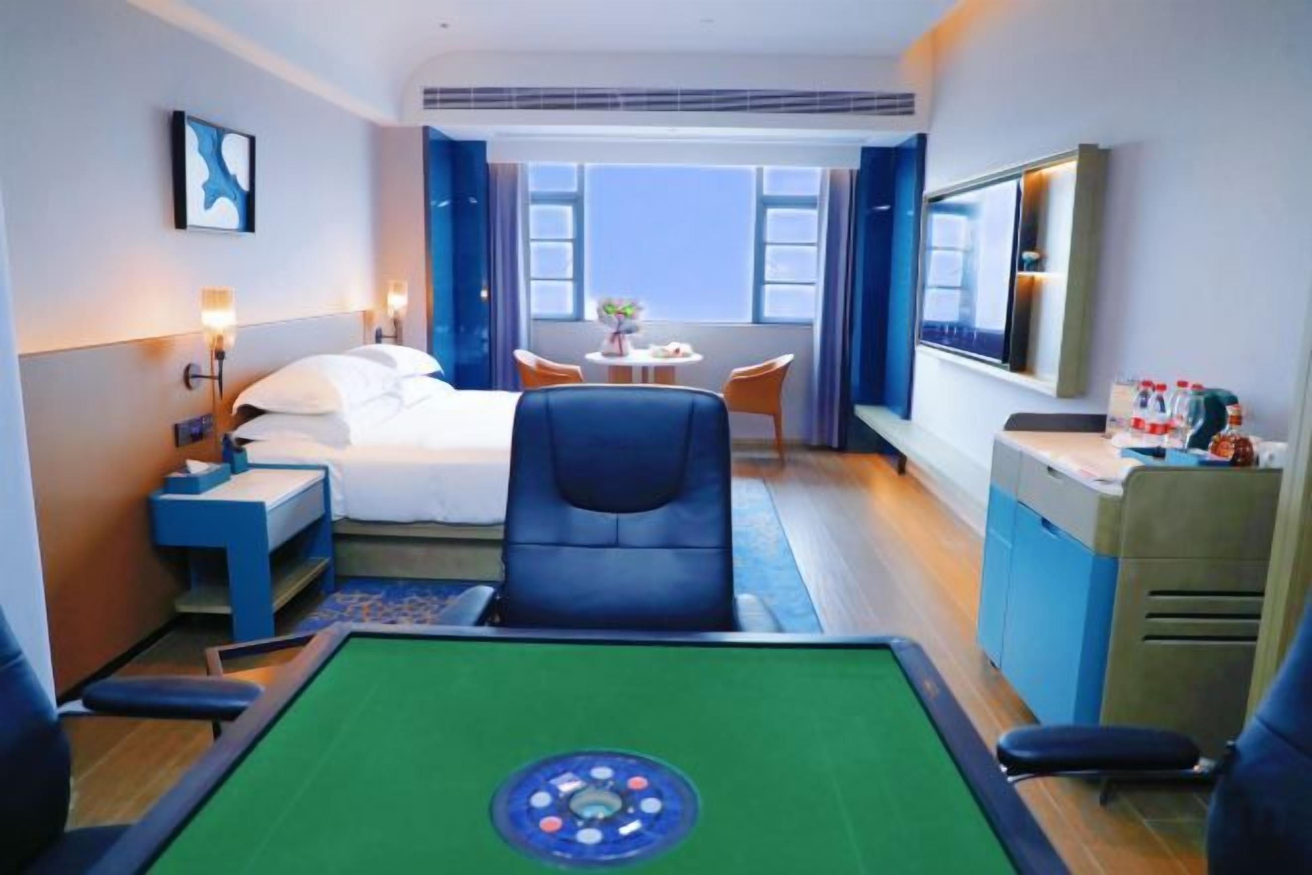 Habitación de hotel con cama, escritorio, silla, mesa de billar y vistas al exterior.
