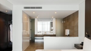 Een moderne hotelkamer met een groot bed, een aparte badkamer met bad en een inloopkast.