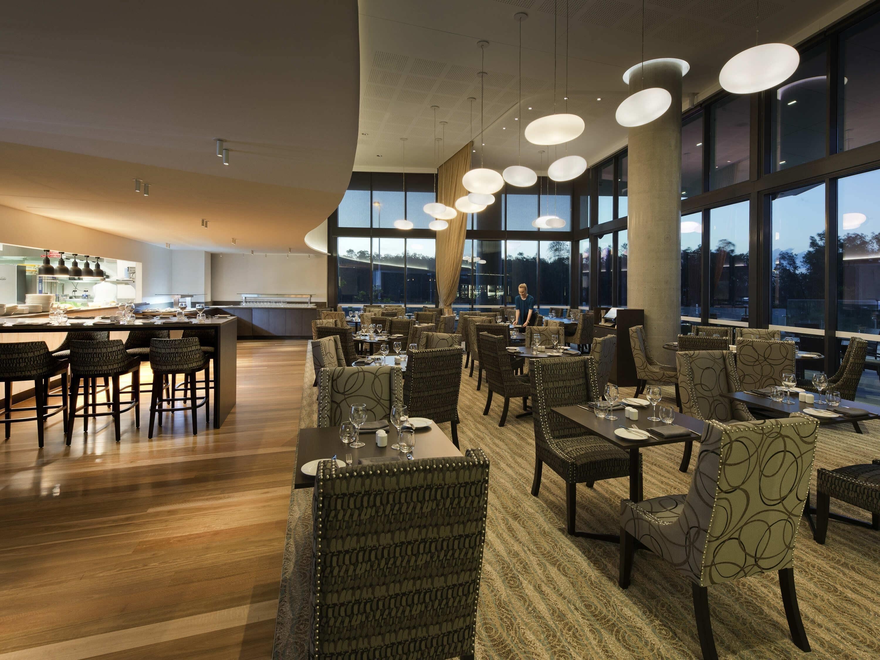 Un restaurante moderno con una zona de bar, mesas y sillas.