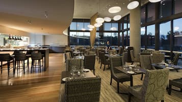 Un restaurante moderno con una zona de bar, mesas y sillas.