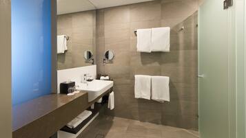 Un baño moderno con un espejo grande, un lavabo y una zona de ducha.