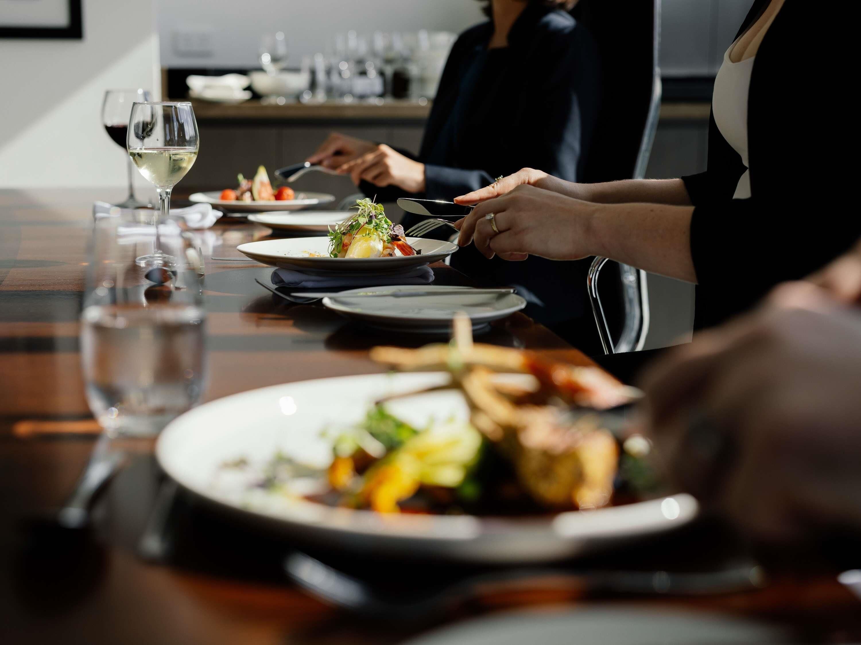Une table à manger avec des assiettes remplies de nourriture, des verres de vin et des couverts.