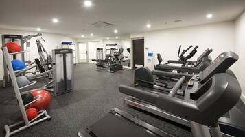 Een fitnessruimte met cardioapparatuur, krachtapparaten en fitnessballen.