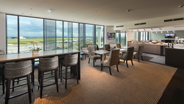 Een moderne hotelkamer met grote ramen en uitzicht op een luchthaven en stadsbeeld.