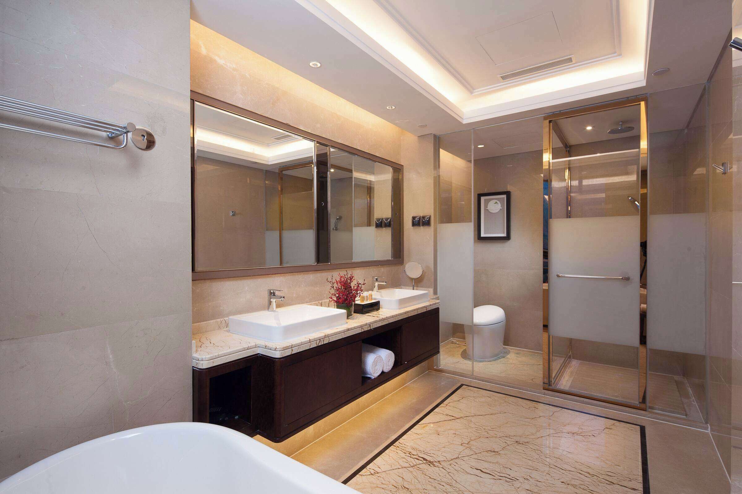 A modern bathroom with a large mirror, two sinks, a bathtub, and a walk-in shower.