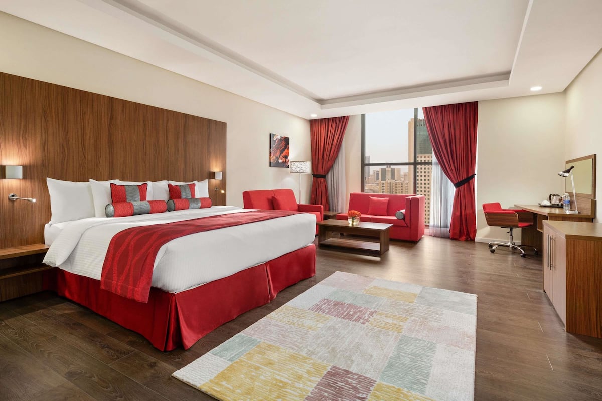 Una habitación de hotel moderna con una cama grande, decoración en rojo y blanco, un escritorio y vistas a la ciudad.