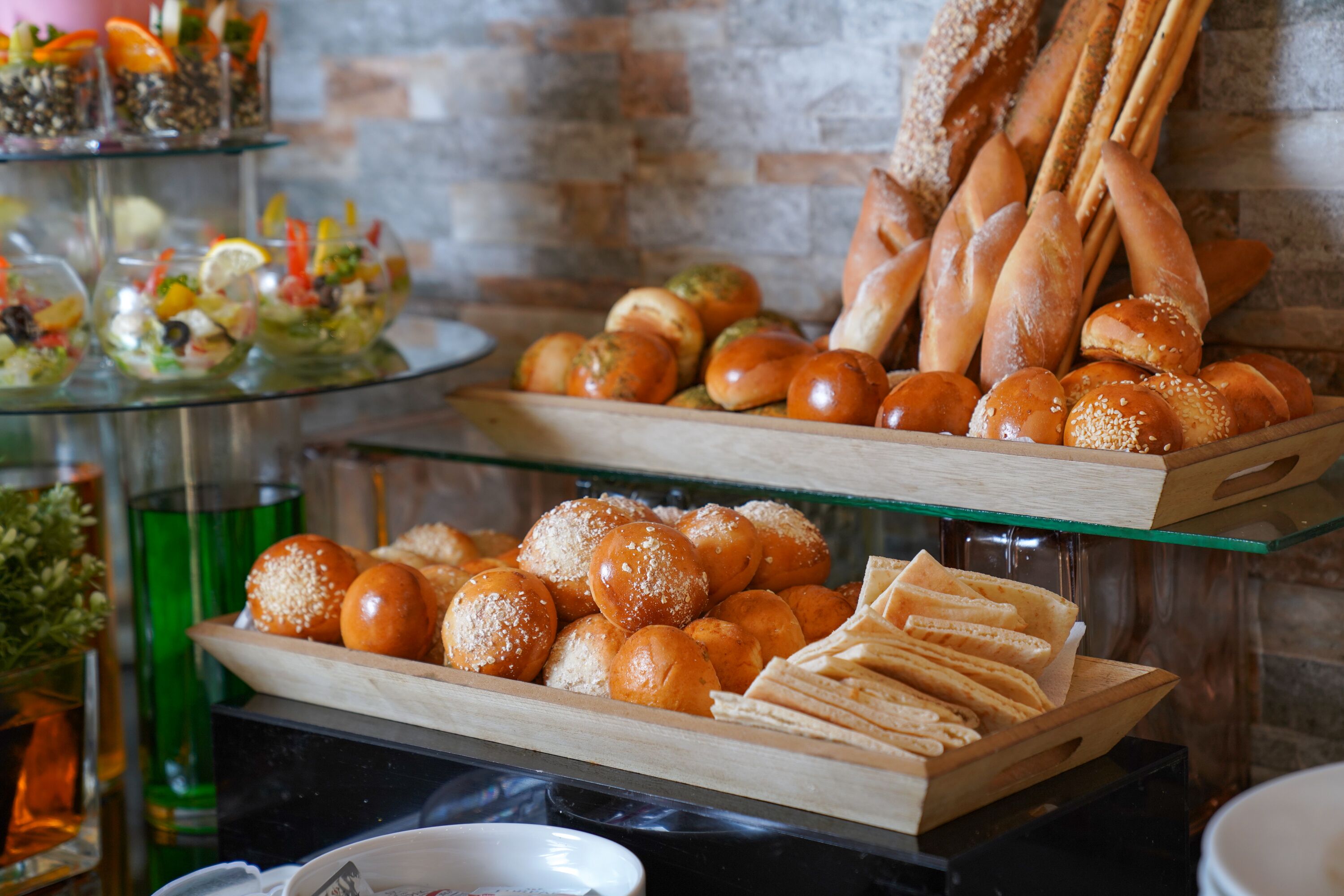 A buffet with various food items including bread rolls, pastries, and a salad.