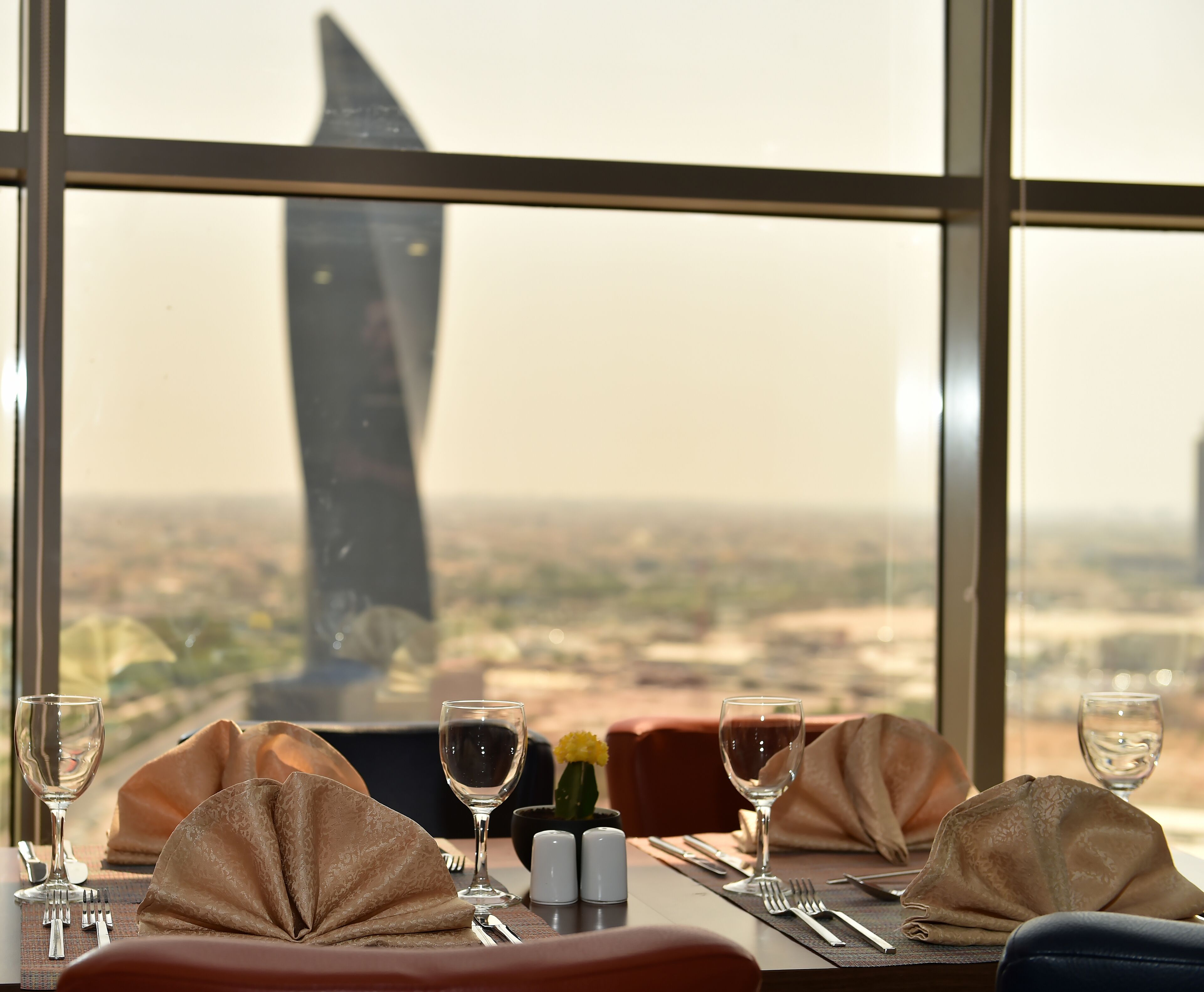Una mesa dispuesta para comer, con vista a un edificio alto y un paisaje desértico.