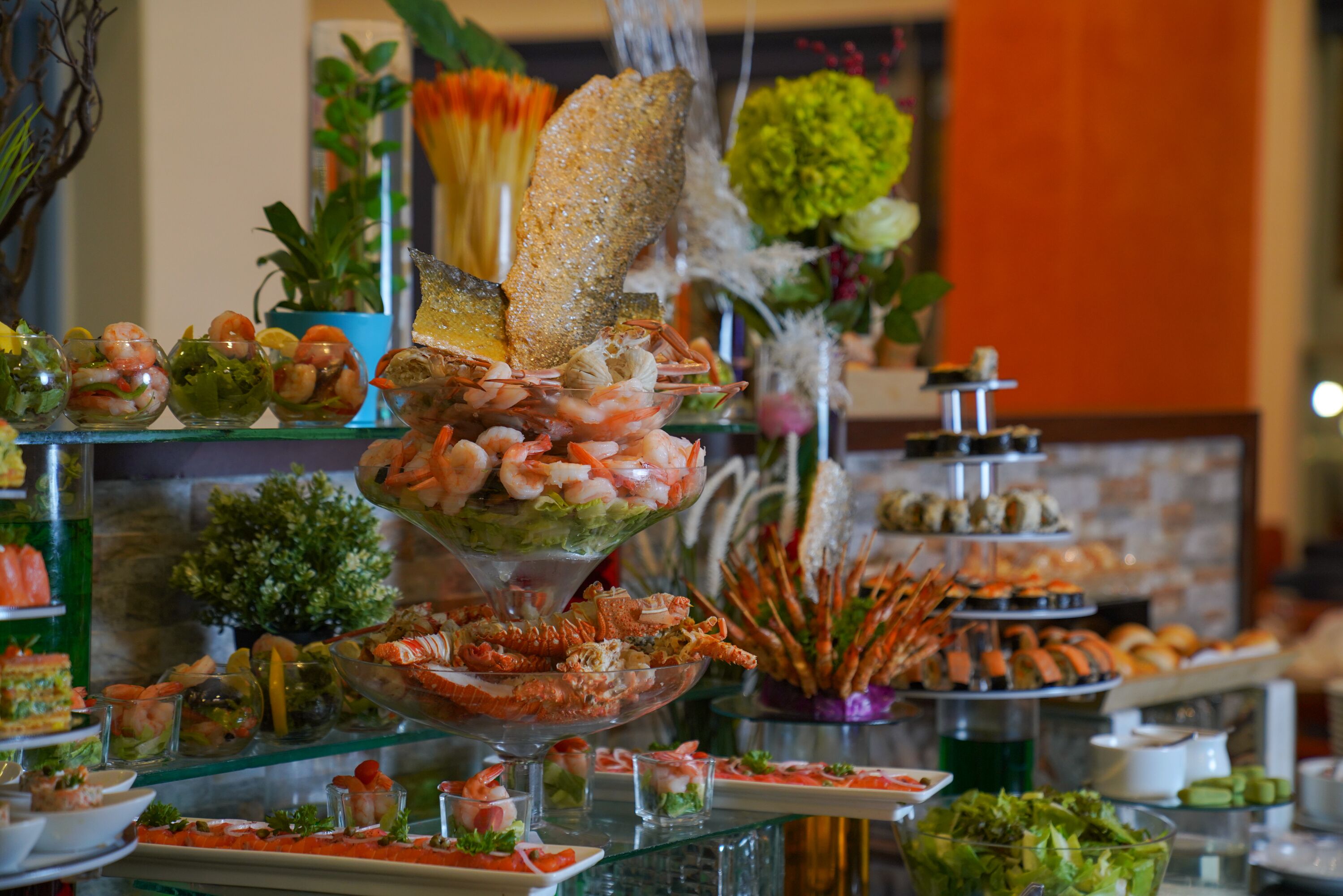 Un bufé con diversos platos de mariscos, como camarones y langosta, dispuestos en estantes de vidrio.