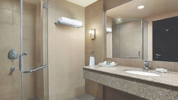 A modern bathroom with a glass-enclosed shower, a granite countertop sink, and a large mirror.