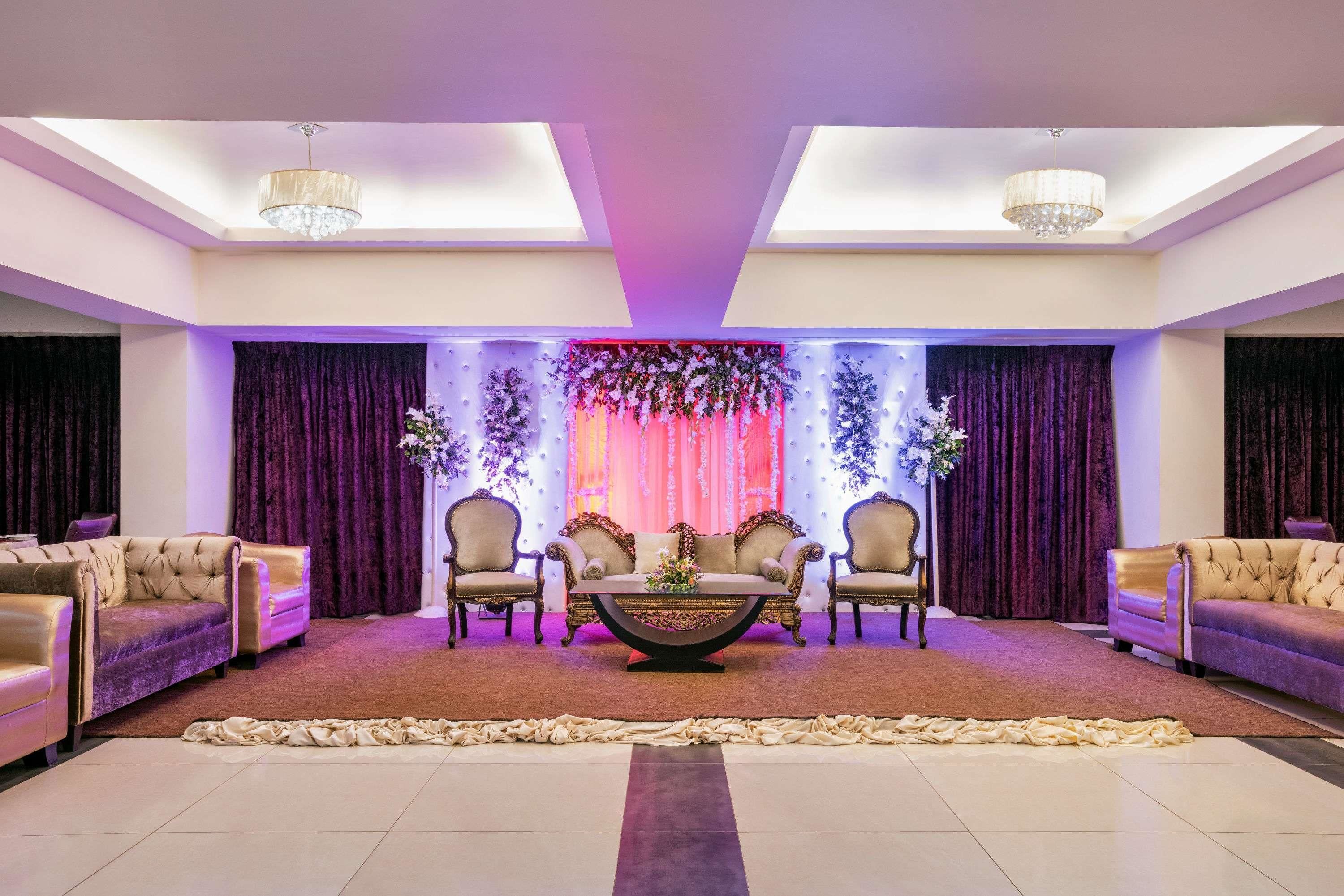 A spacious room with a central seating area featuring a round table, surrounded by sofas and armchairs.