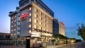 Een meerlaags hotel met een opvallend ‘RAMADA’ bord, grote ramen en een goed verlichte gevel.