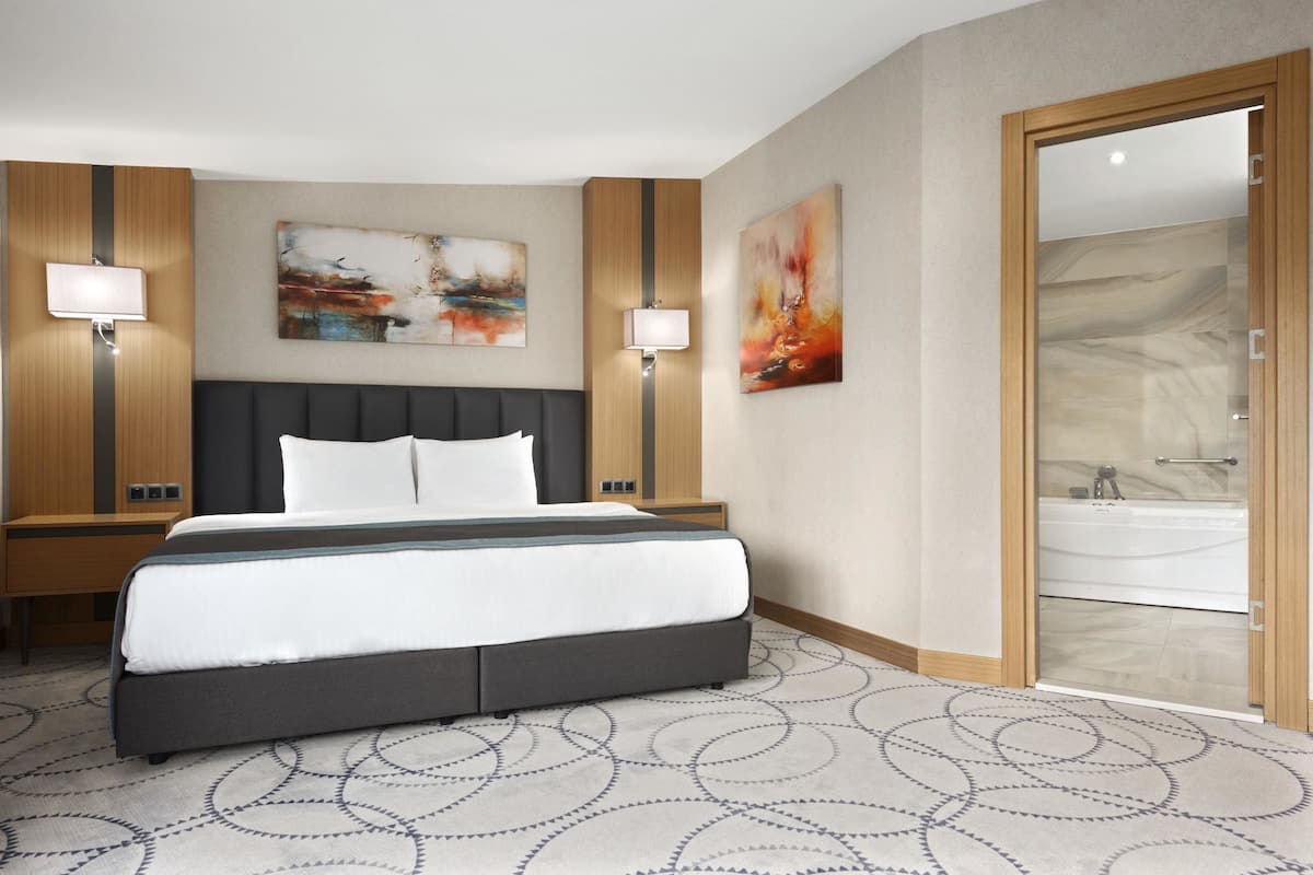 Ein Hotelzimmer mit einem großen Bett, zwei Nachttischen, einer Wandleuchte und einem Gemälde.