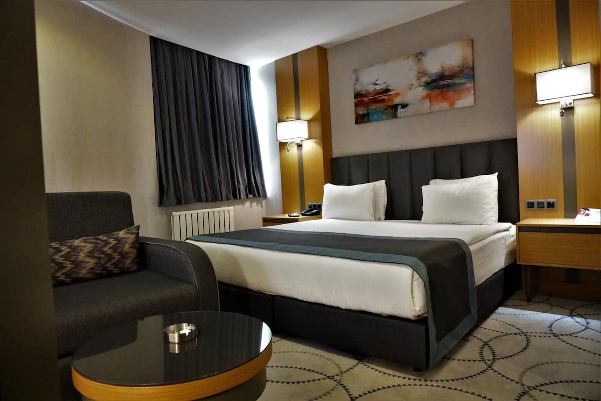 Ein Hotelzimmer mit einem Bett, einem Sofa, einem Couchtisch und einem Gemälde an der Wand.