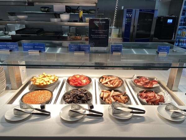 A buffet with various food options including baked beans, mushrooms, bacon, and sausages.