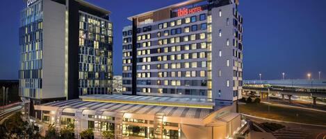 A hotel with a modern design, featuring a prominent 'Pullman' sign and a 'Hilton' sign.
