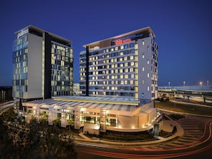A hotel with a modern design, featuring a prominent 'Pullman' sign and a 'Hilton' sign.