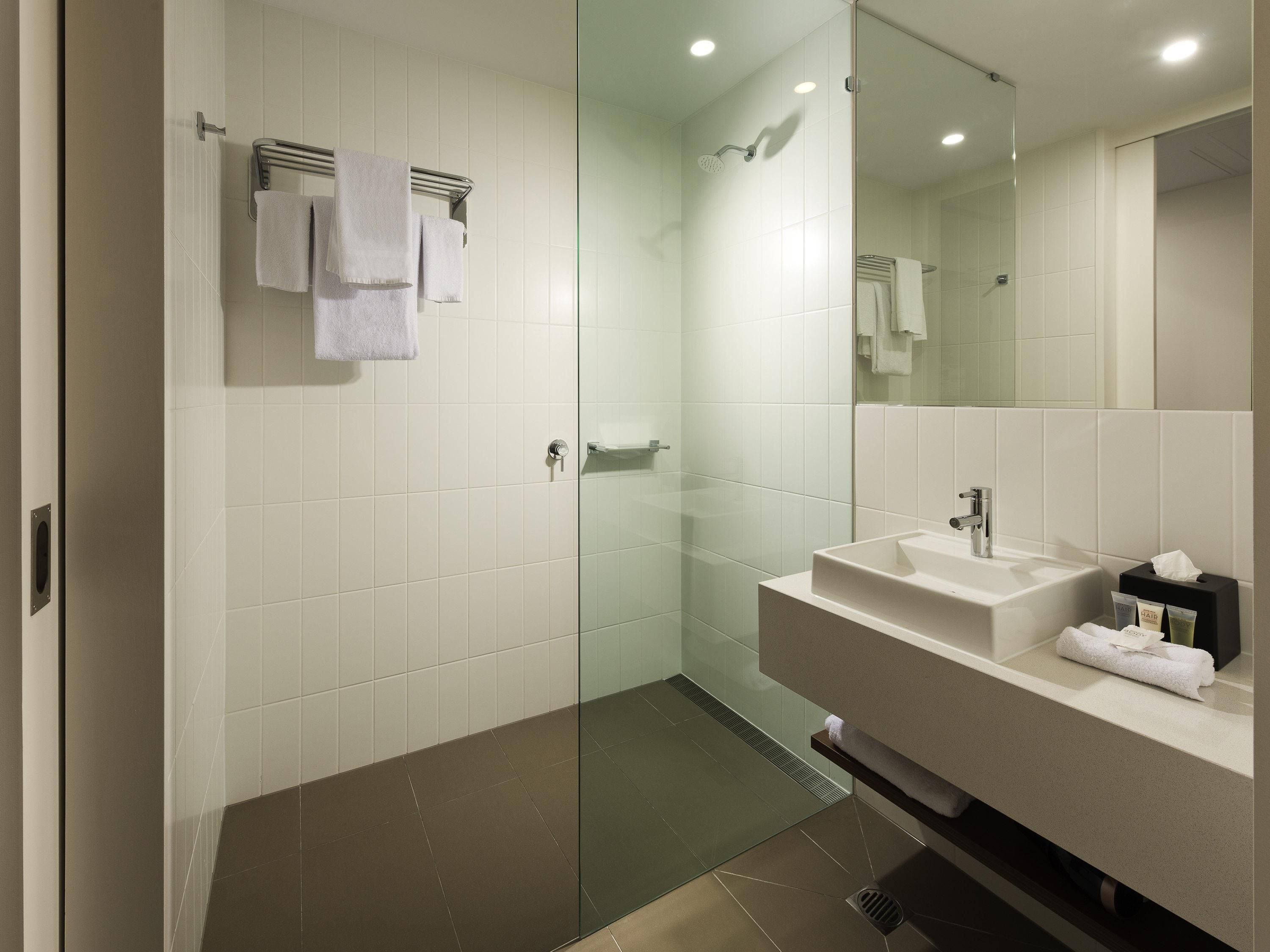 A modern bathroom with a glass shower enclosure, a white sink, and a mirror.