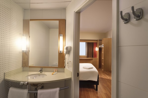 Ett hotellbadrum med en stor spegel, handfat och handduksställ.