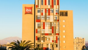 A multi-story hotel with a distinctive facade featuring a mix of geometric patterns and a prominent logo. - ibis Copiapo (Copiapó)