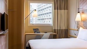 A hotel room with a bed, a desk with a laptop, a TV, and a window with curtains. - ibis Copiapo (Copiapó)